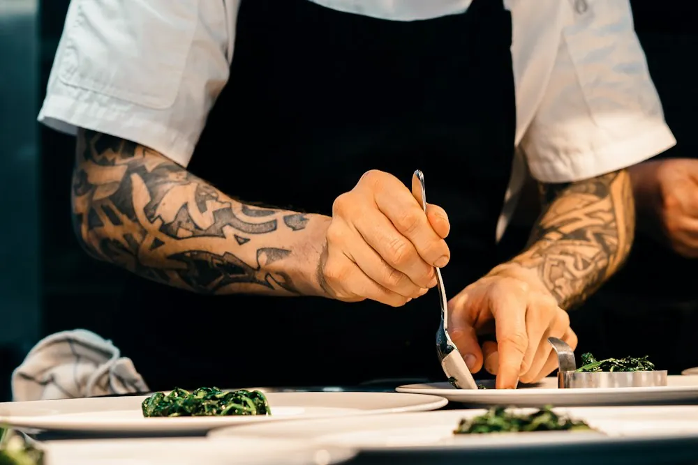 Kucharz nakłada danie na talerz w restauracyjnej kuchni